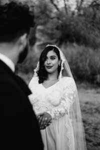 Bride and Groom eloping in Arches National Park in a wedding dress and black suit with a wedding arch.