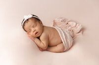 newborn baby girl sleeping in all pink setup