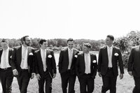 Photo of groom and groomsmen walking outside taken by Boutique wedding photographer Maine