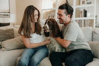 A couple sitting on a couch with their dog
