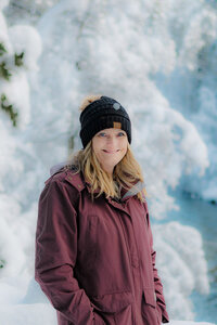 Female photographer in the snow wearing warm jacket and hat.