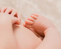 Newborn baby resting hands on cheeks with  milky lips