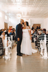 Indoor wedding with kiss in the aisle