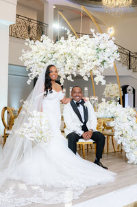 Bride and groom pose for portrait at wedding reception filled with lush white floral installations