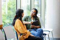 Two women sitting and talking by a window