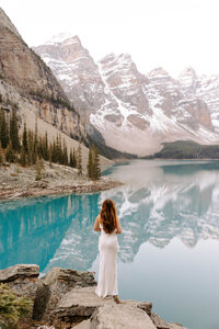 Bride to be poses for a portrait in front of Moraine lake and the mountains of Banff National Park Canada