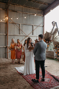 wedding ceremony bride saying vows in rustic farm shed