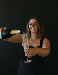 Eugene wedding planner and coordinator Rachel laughs while filling a champagne glass, representing her bubbly personality. 