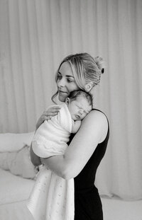 lucy jane, a professional christchurch newborn photographer settles a newborn baby during a photoshoot