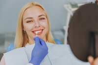 A woman smiling in dental chair reviewing options for dental veneers