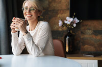 Editor wearing glasses and holding a cup of tea and smiling at the camera