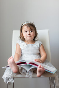 Little girl sitting in chair holding book