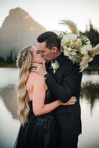A happy couple kiss each other at sunset on their wedding day in Glacier National Park in Montana.