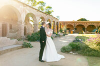 sunset wedding photography of bride and groom looking at each other at mission san juan capistrano
