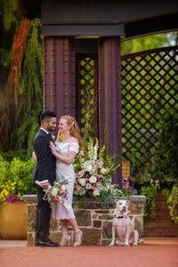 Couple celebrating their elopement with elegant floral arrangements and their dog by their side.