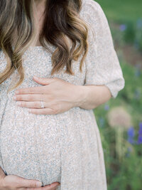 A close-up of a woman holding her pregnancy bump during a maternity photography session in Richmond by Katie Stansfield Photography.