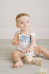 One year old baby boy looks up while playing with blocks