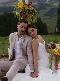 bride and groom sitting back to back at their elopement picnic