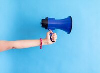 Hand holding blue megaphone on bright background