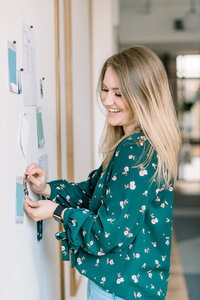 Woman smiling while placing something on the wall