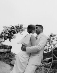 mixed race couple kissing in front of their circular ceremony backdrop in tofino