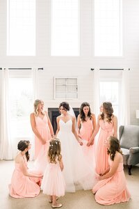 Bridemaids helping bride get her wedding dress on in the getting ready room