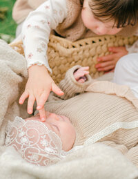 Toddler girl reaches out to her infant baby sister during a family photoshoot in Vondelpark. 