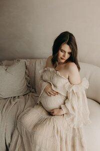Serene maternity portrait of an expectant mother with dark hair in a soft white gown in Mullingar