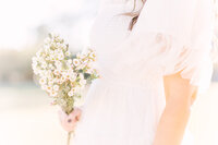 Photo of a beautiful bouquet of wild flowers  and the bust of a woman in a white dress