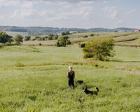 Sasha standing in grassy field with dog on the farm