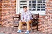 High school senior guy in a button down shirt sitting on a bench in downtown Lexington, SC