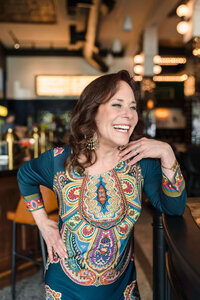Woman in Kelowna cafe wearing colourful dress posing for brand photos.