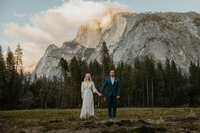 bride and groom holding hands in front of a mountain