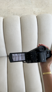 Close-up of a camera in hand near a white couch