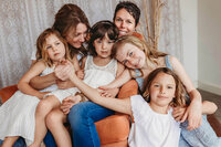 Two mothers sitting and cuddling with their four small daughters.