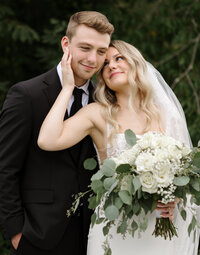 Bride holding groom's face and looking up at him