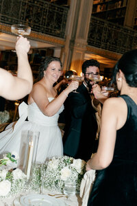 A bride and groom share a toast, surrounded by family and friends. Captured by Caitlin Wilcox Photography, a Virginia wedding photographer