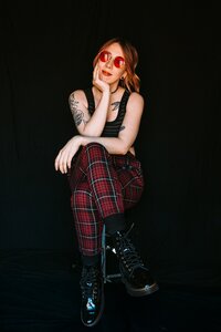 An alternative, non-traditional Connecticut wedding photographer wearing plaid red pants sitting in front of a dark background