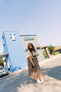 Allison Bolin Texas wedding photographer standing in front of a Dutch Bros Coffee with coffee and a camera