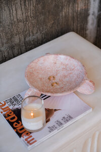 decorative bowl with gold hoop earrings on top a Marie Claire magazine and next to a candle 