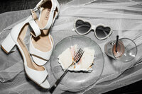 wedding reception flat lay with cake , glasses, and shoes