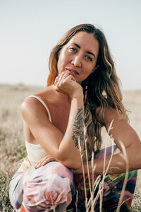 Portrait of a yoga and movement instructor, her chin resting in her hand as she looks directly at the camera