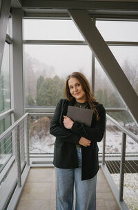 Girl with brown hair and blue eyes holding camera and smiling at camera