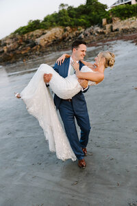Photo of groom carrying bride through water taken by Portland Maine wedding photographer