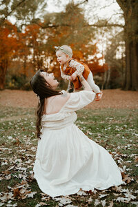 Warm fall family moment with a mom lifting her baby in the air, photographed by Charlotte family photographer Tonya Cassibry.