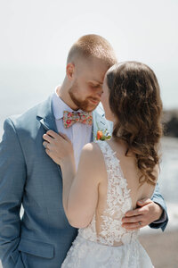 A newlywed couple with their arms around each other and their heads touching 
