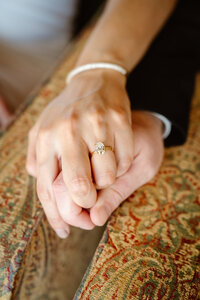 A close up of two hands featuring an engagement ring
