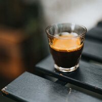 small glass of espresso on a black slatted table