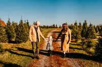 Brother and sister hugging each other at a christmas tree farm with sunset behind them
