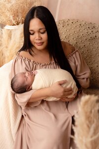 Newborn baby held by a smiling mom during a newborn photography session in Summerside, Edmonton by Claudia De La Torre